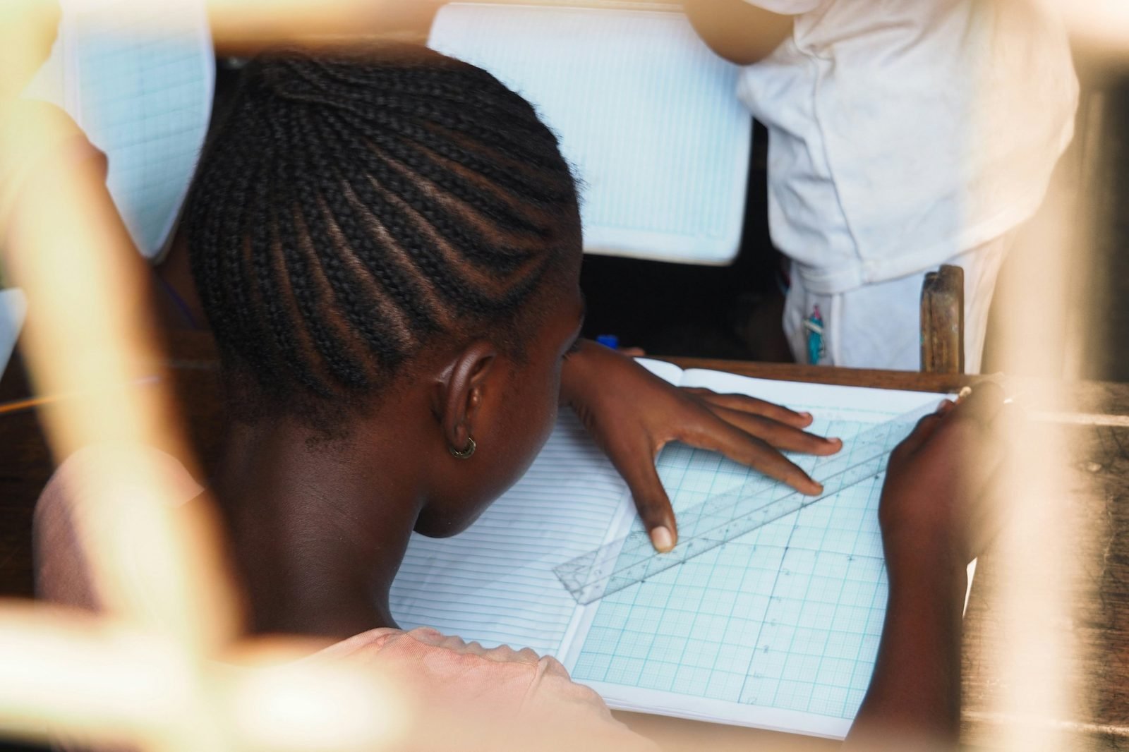 Une élève trace des lignes à la règle sur son cahier